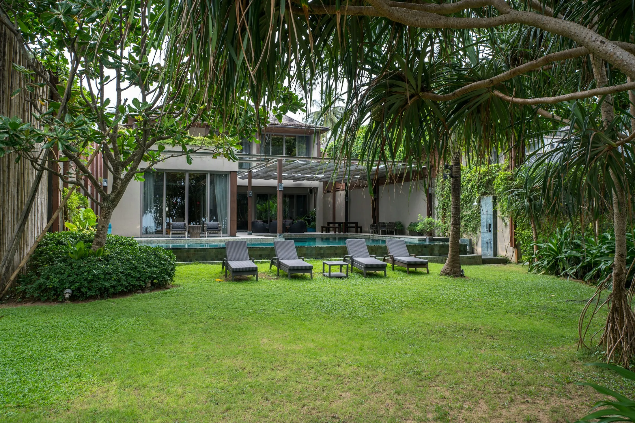 A secluded tropical villa garden with lounge chairs, palms, and a private pool