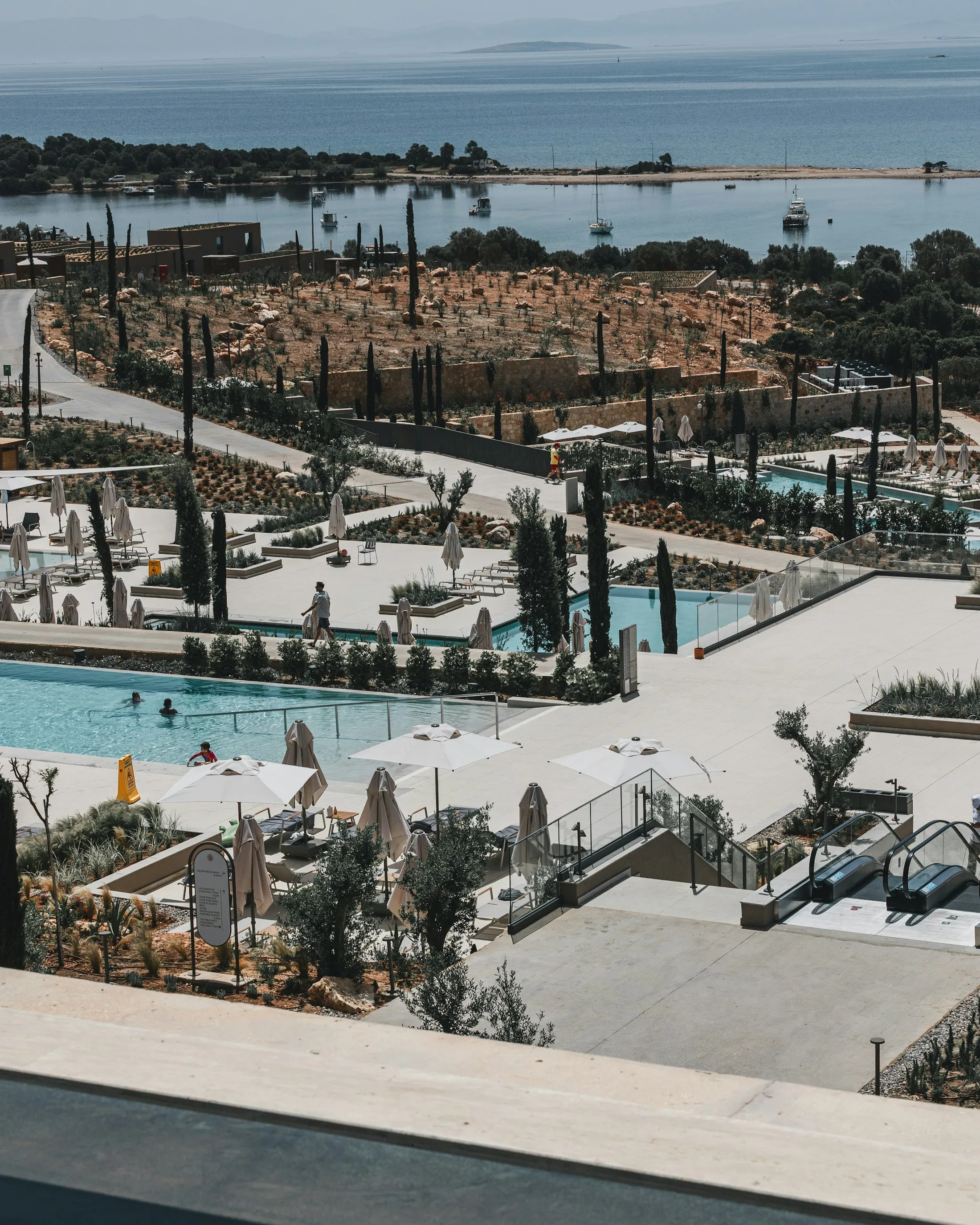 Outdoor luxury resort loungers and white umbrellas arranged beside pools near the sea