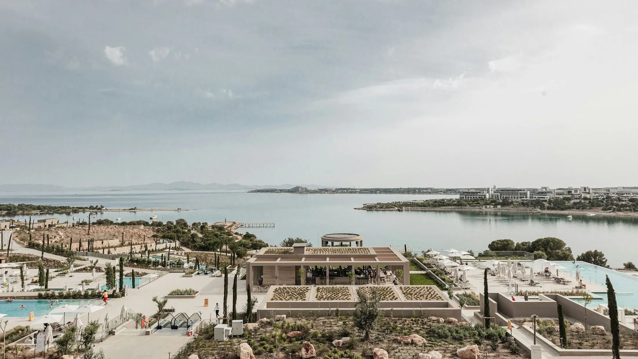 Luxury resort pools overlooking a quiet bay with boats under a hazy sky