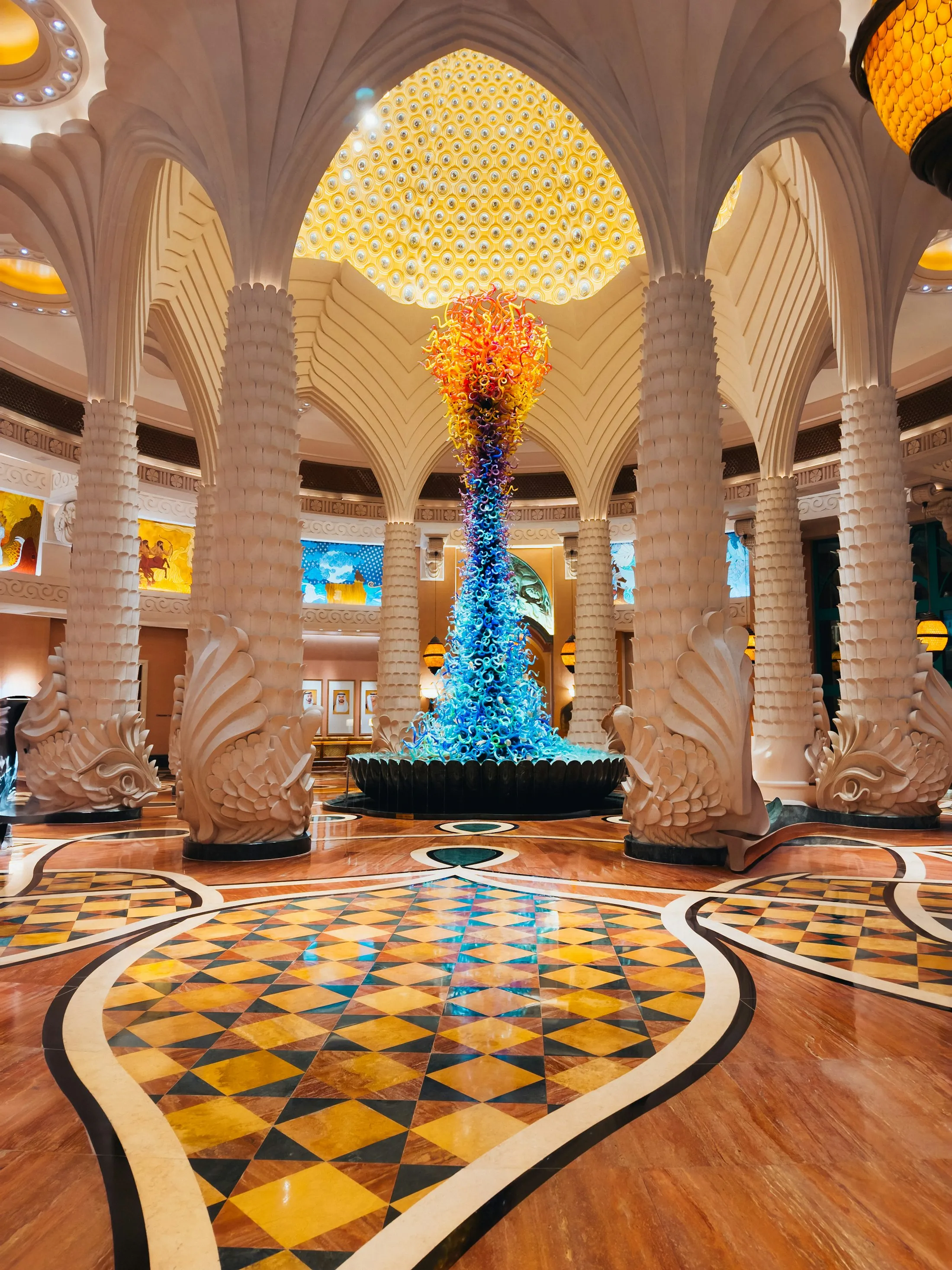 Grand hotel lobby with ornate columns and a colorful glass sculpture