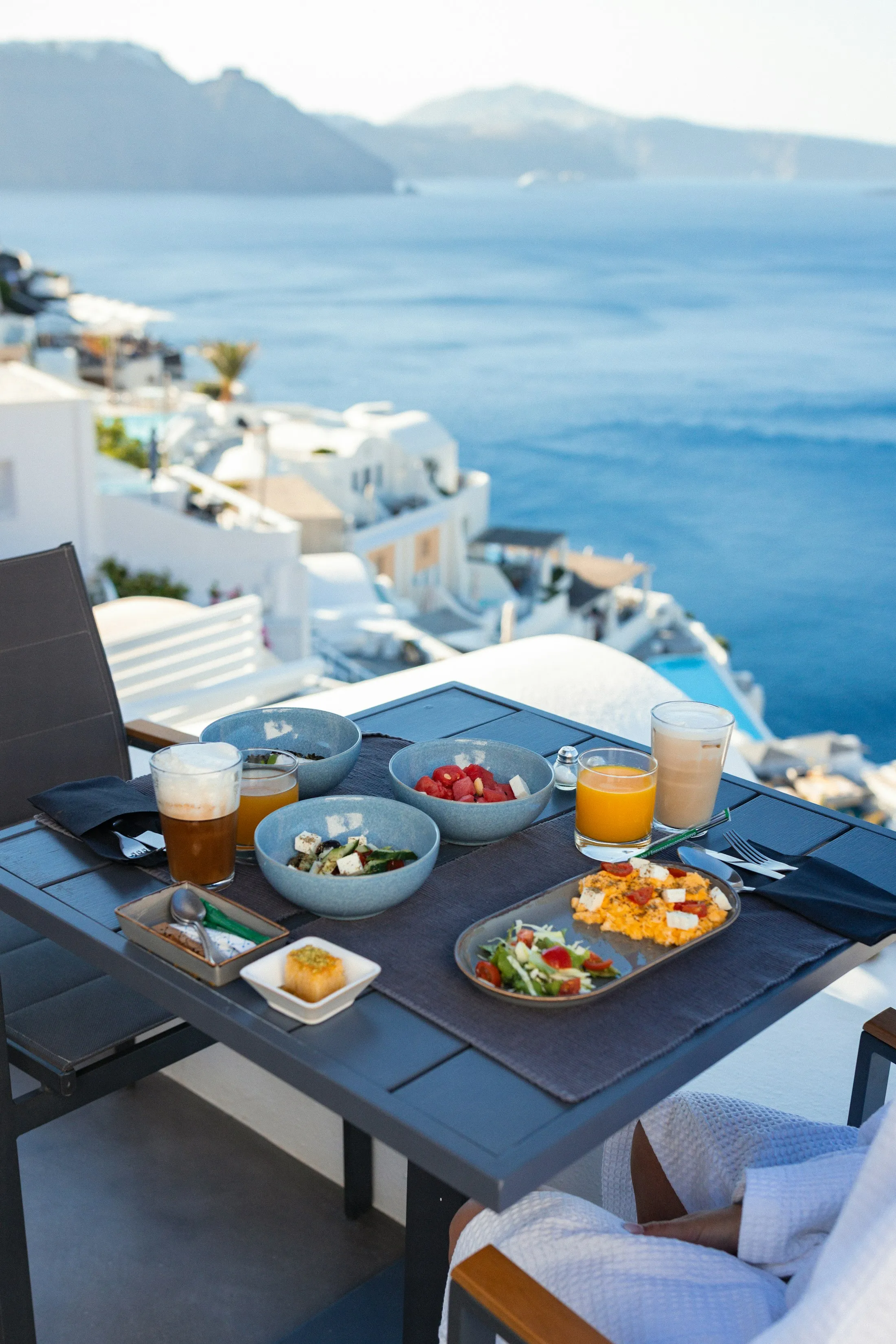 Breakfast set on a balcony overlooking white coastal buildings and blue sea